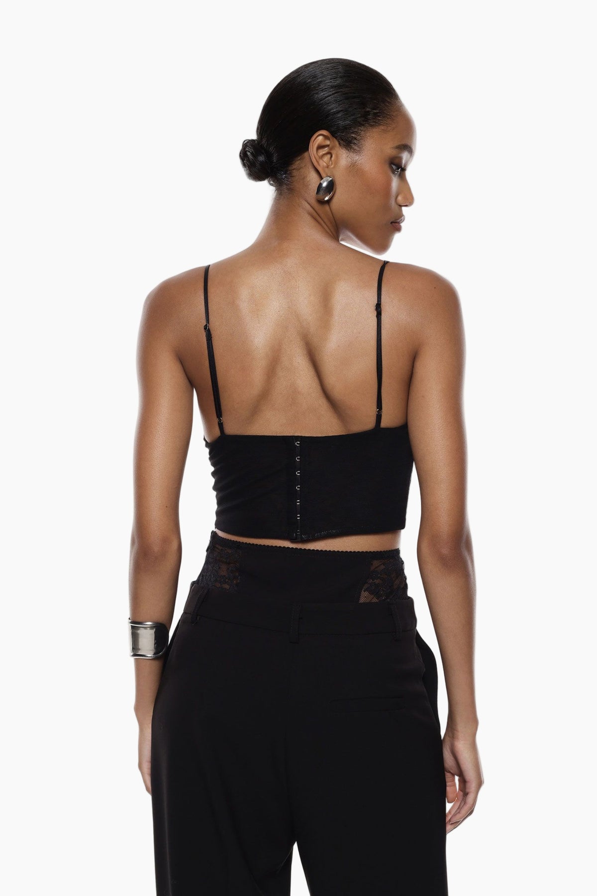 Woman wearing a black sleeveless top with buttons and high-waisted black pants