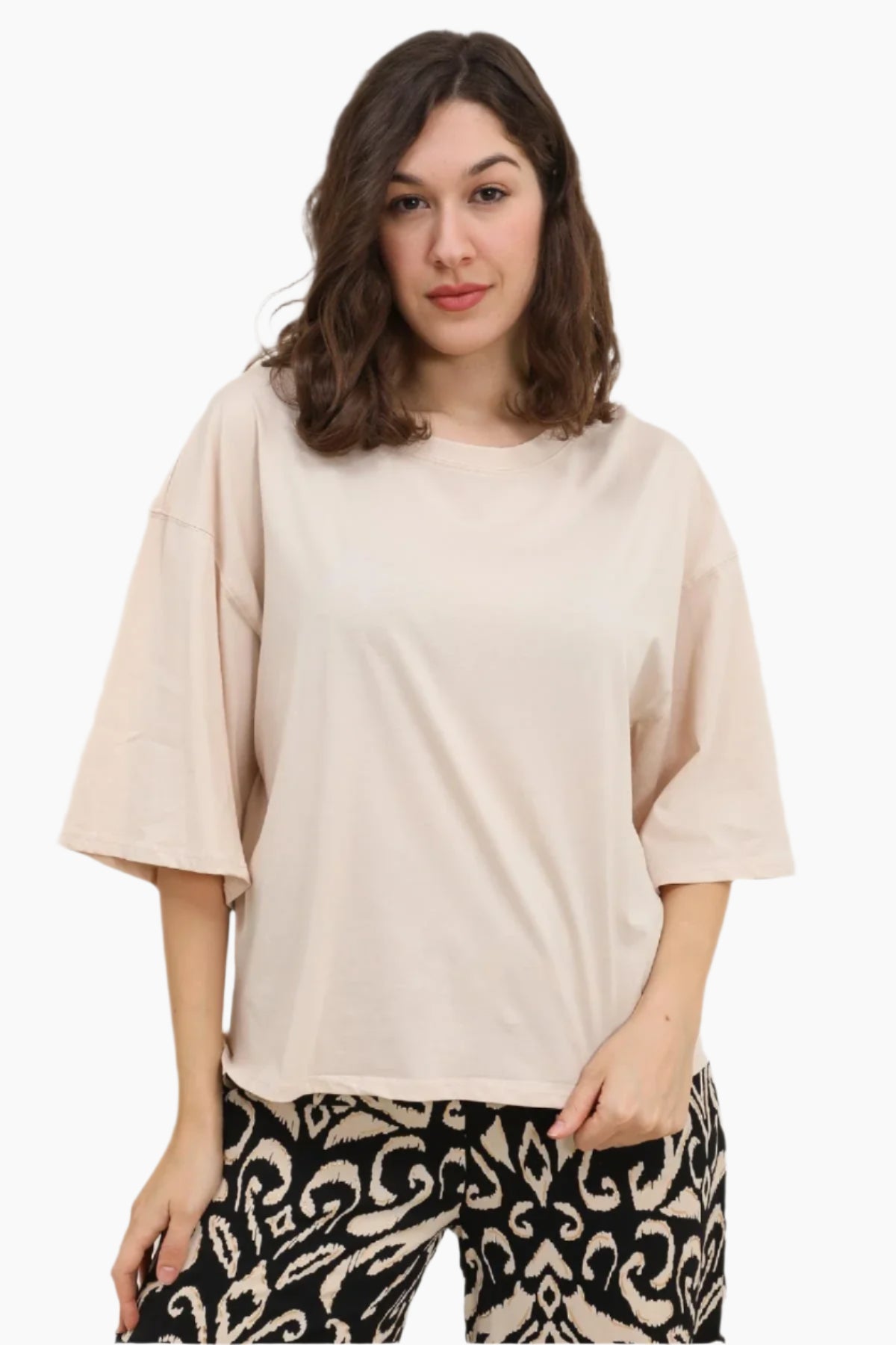 Woman wearing a beige oversized top and patterned pants