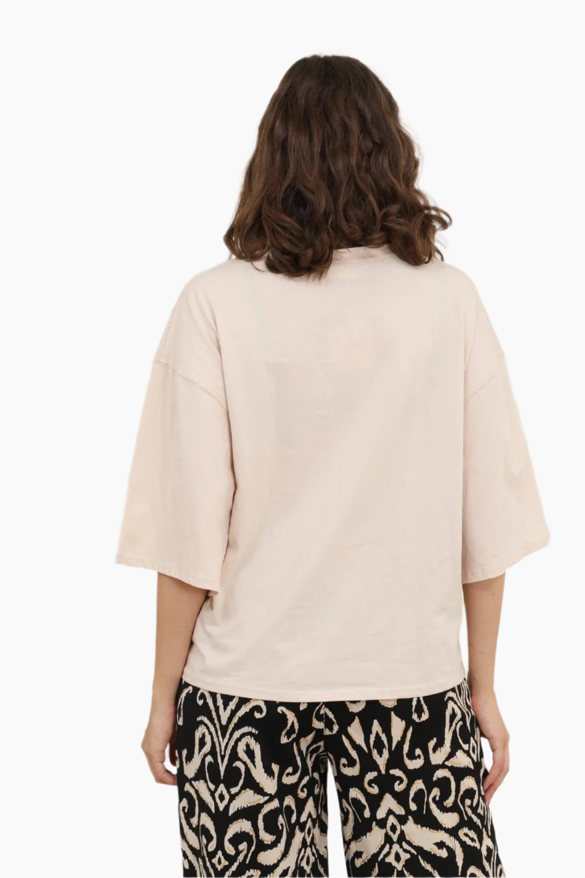 Person wearing a beige oversized shirt with patterned pants