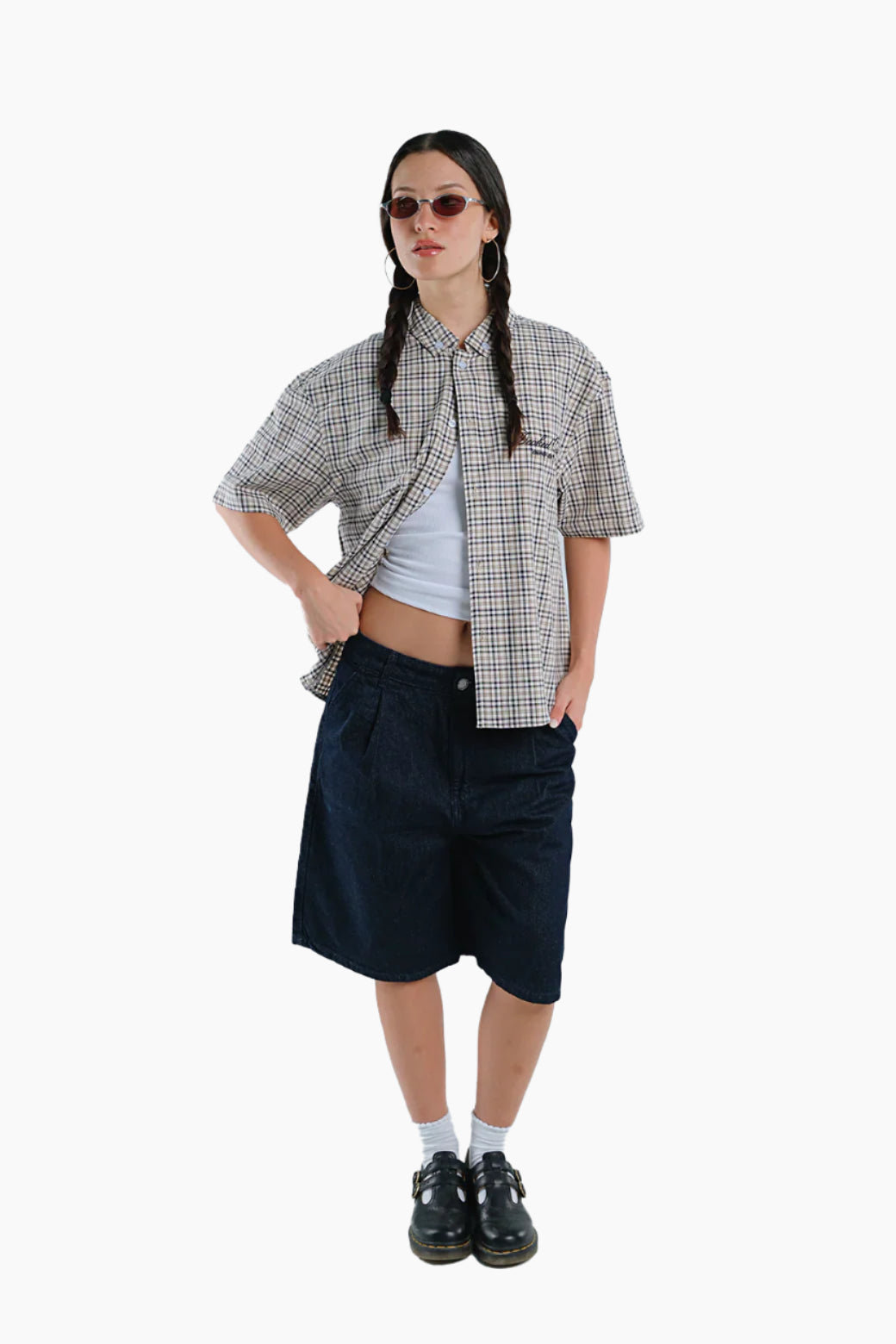 Person wearing a plaid shirt, white crop top, and navy shorts
