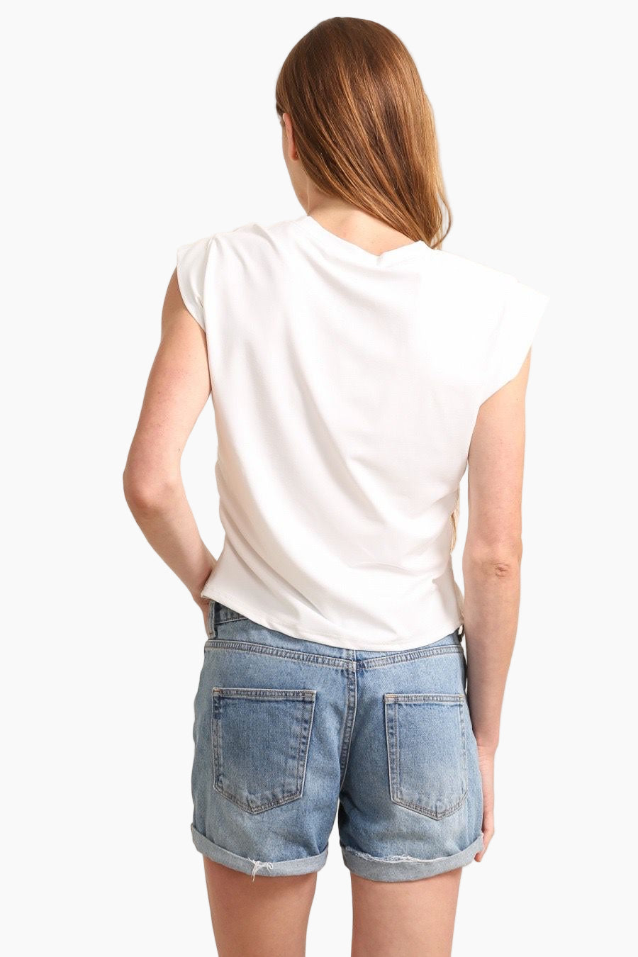 Person wearing a white sleeveless top and denim shorts