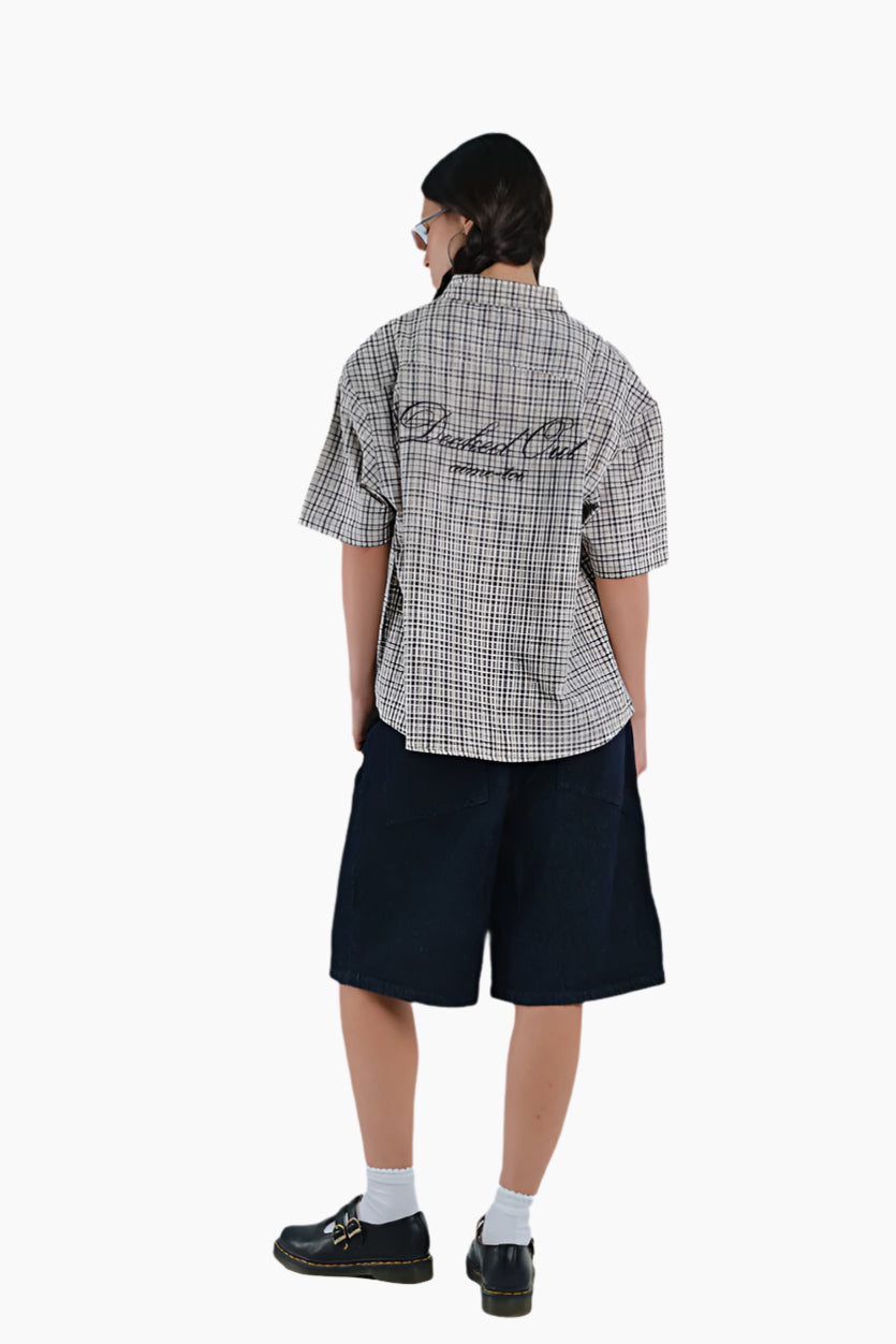Person wearing a checkered shirt with branding and black shorts