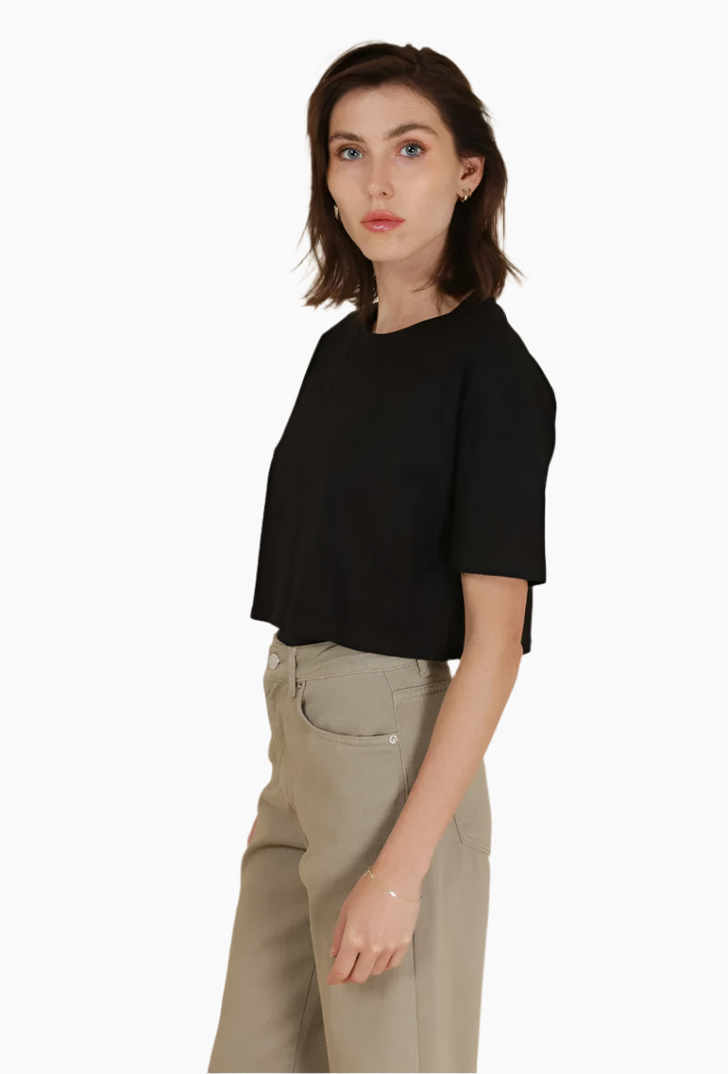 Woman wearing a black top and beige pants on a white background
