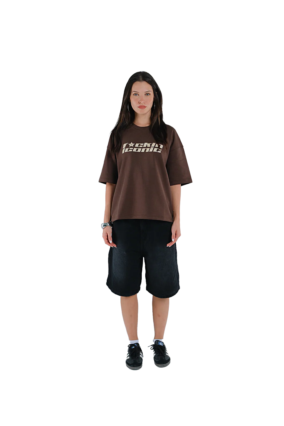 Person wearing a brown oversized t-shirt with text and black shorts