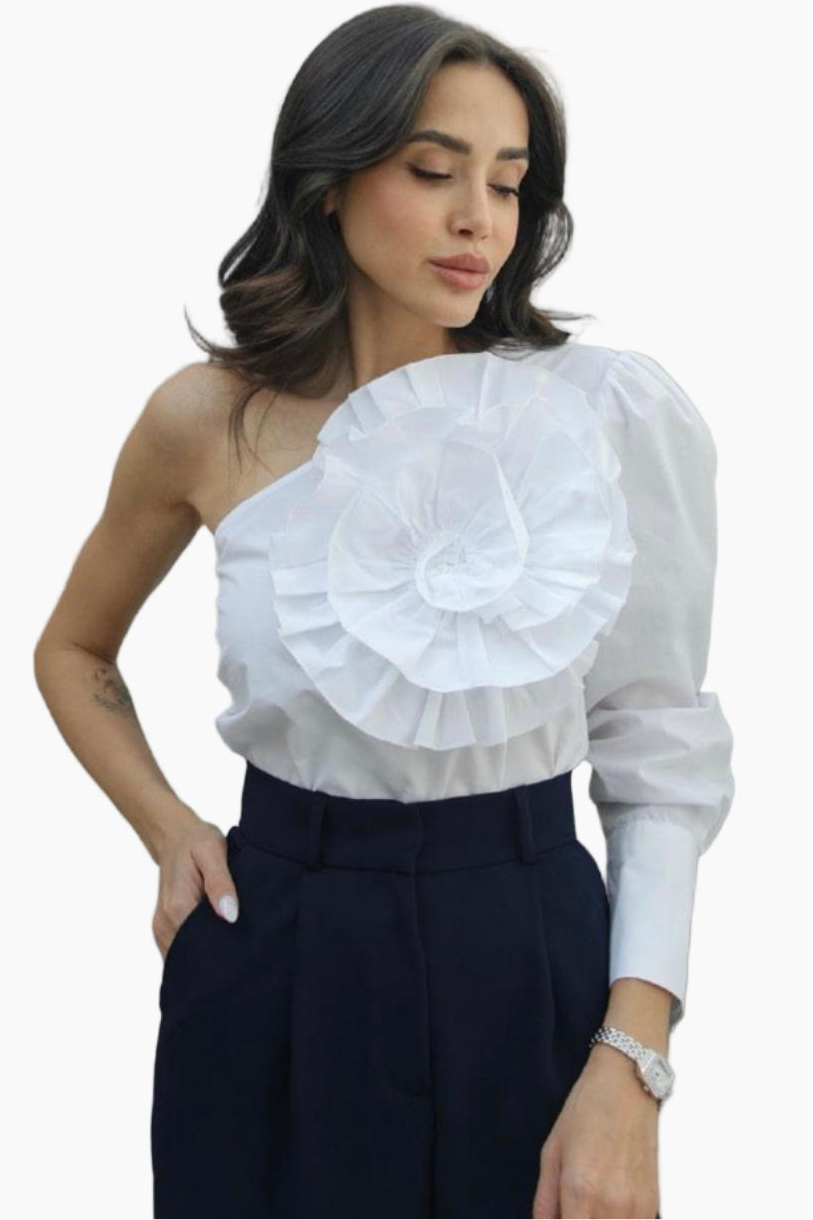 Woman wearing a white one-shoulder blouse with ruffled details on a white background