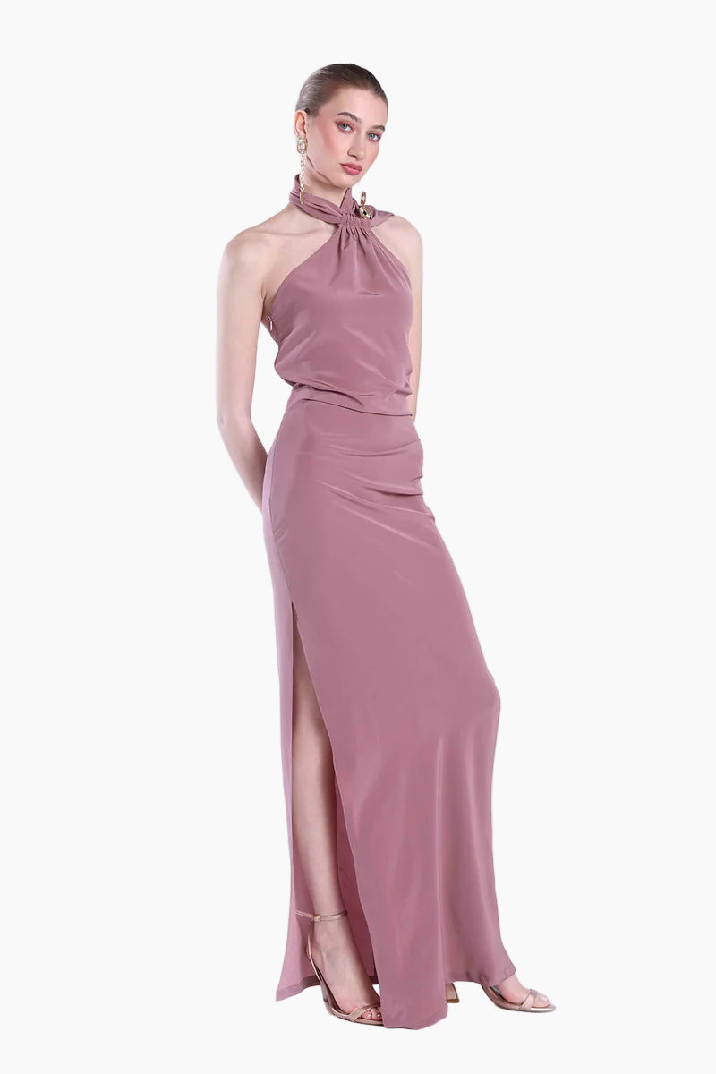 Woman wearing a mauve evening gown with a high slit on a white background