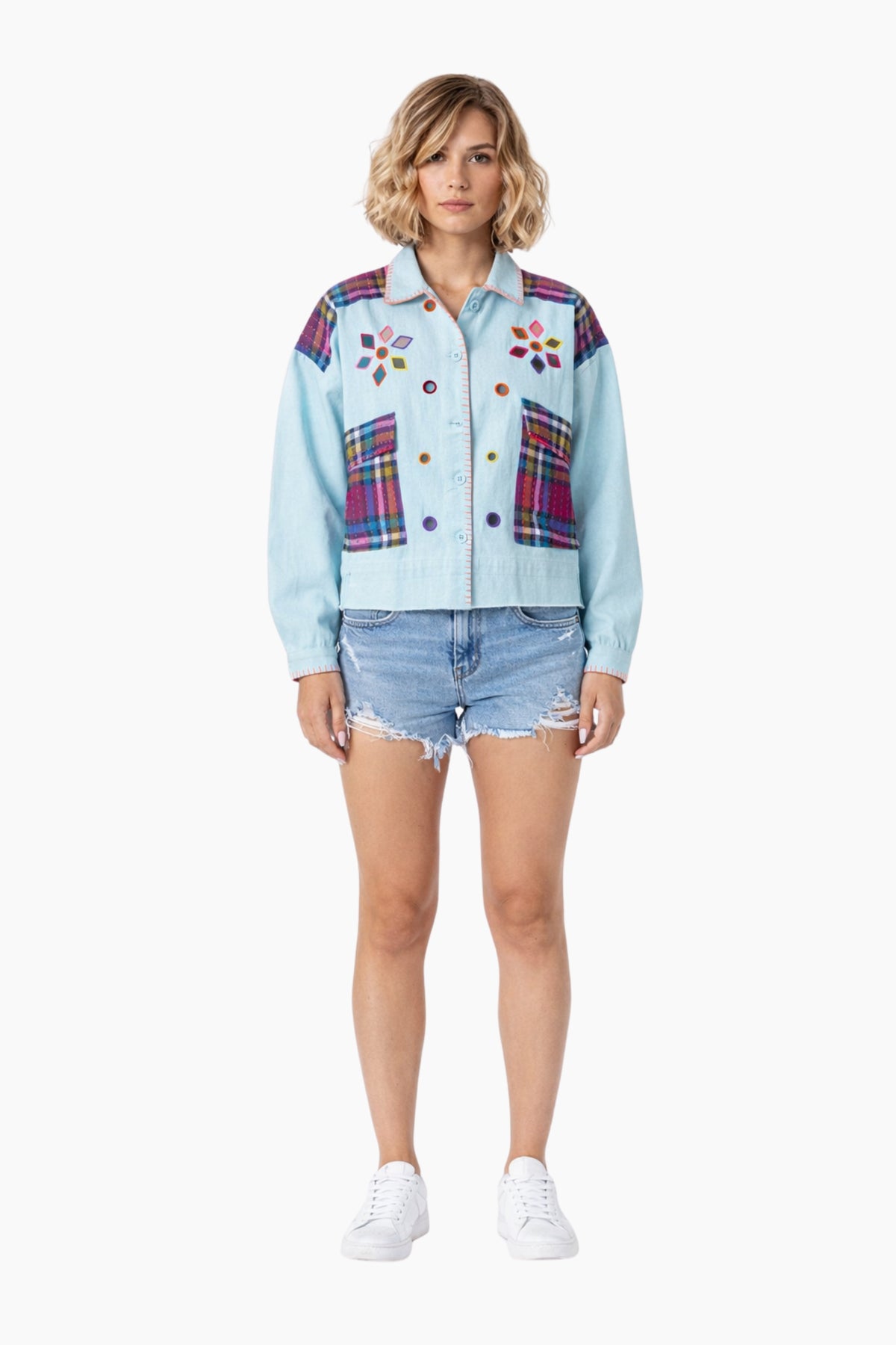 Woman wearing a light blue denim jacket with colorful plaid patterns on a white background