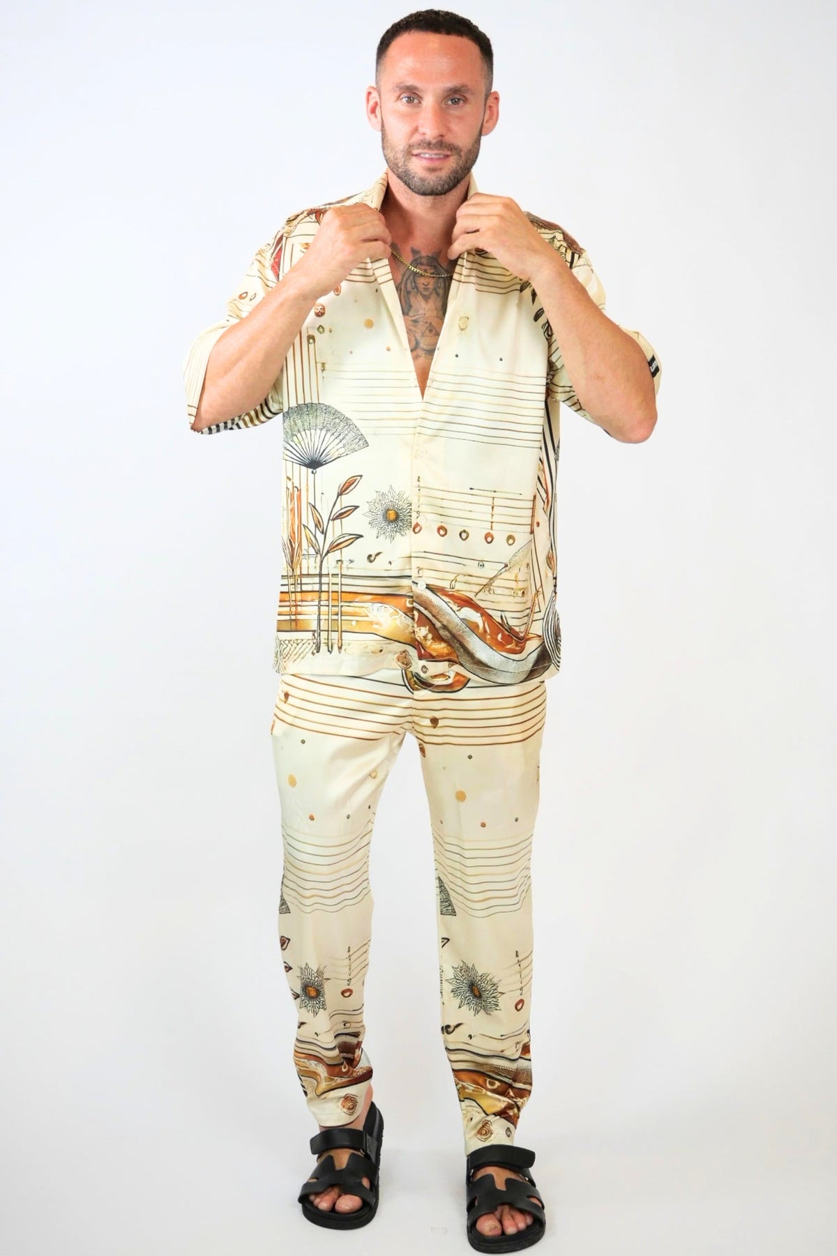Man wearing a stylish outfit with floral and musical note patterns on a white background