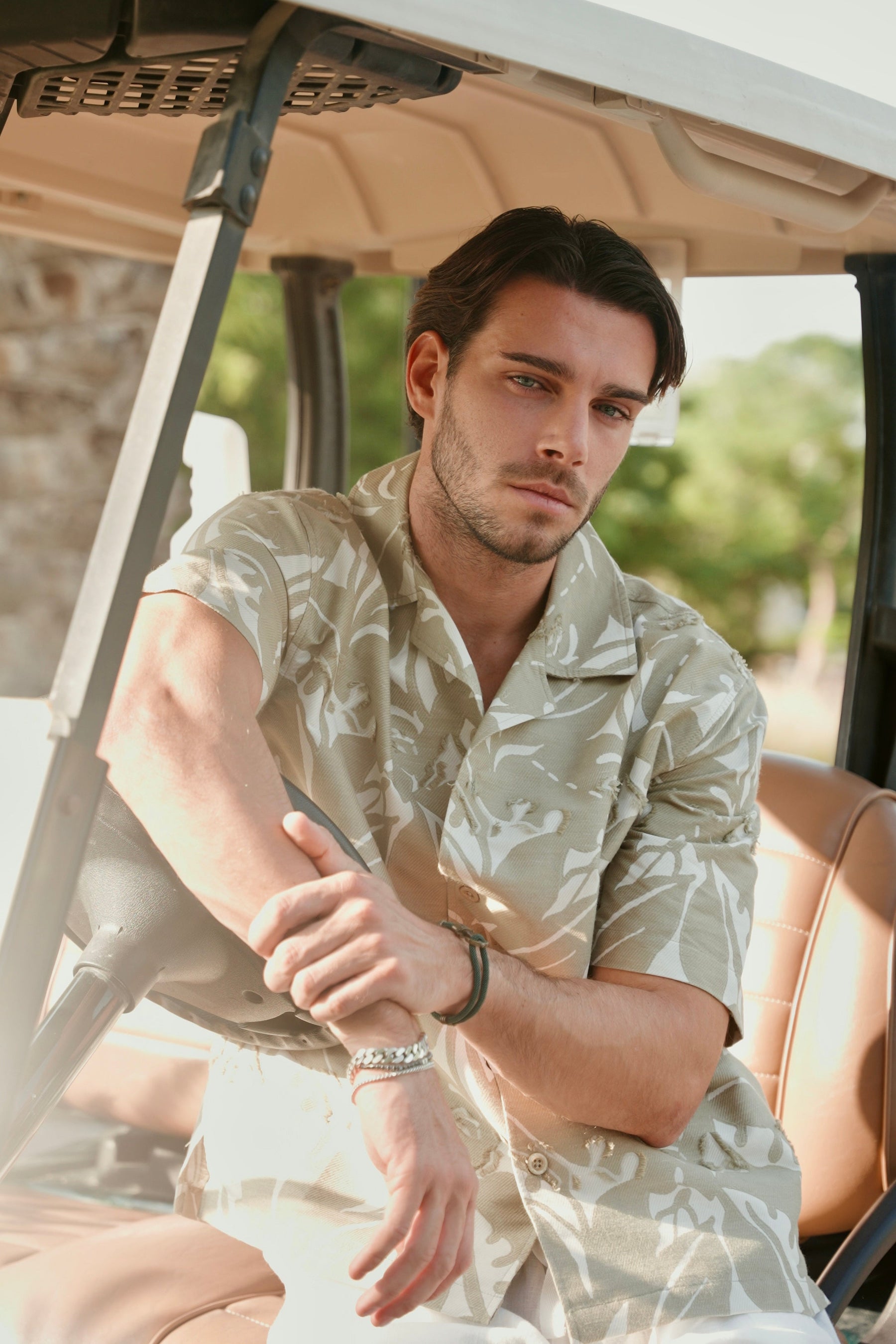 Man sitting in an open-top vehicle wearing a camouflage shirt