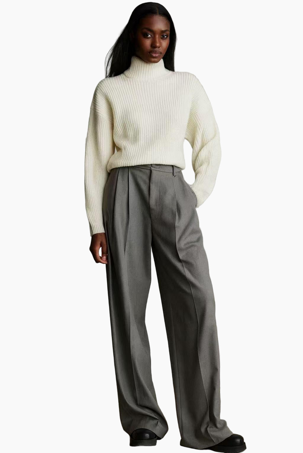 Person wearing a white turtleneck sweater and gray pants