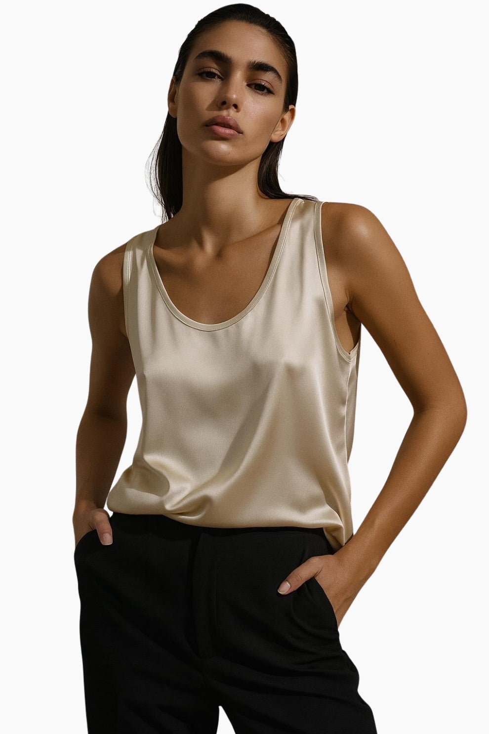 Woman wearing a beige satin tank top and black pants