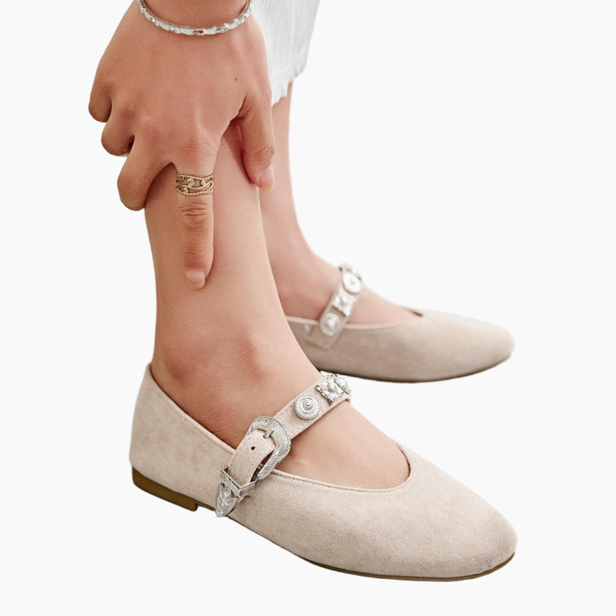 Beige flats with silver buckles worn by a person