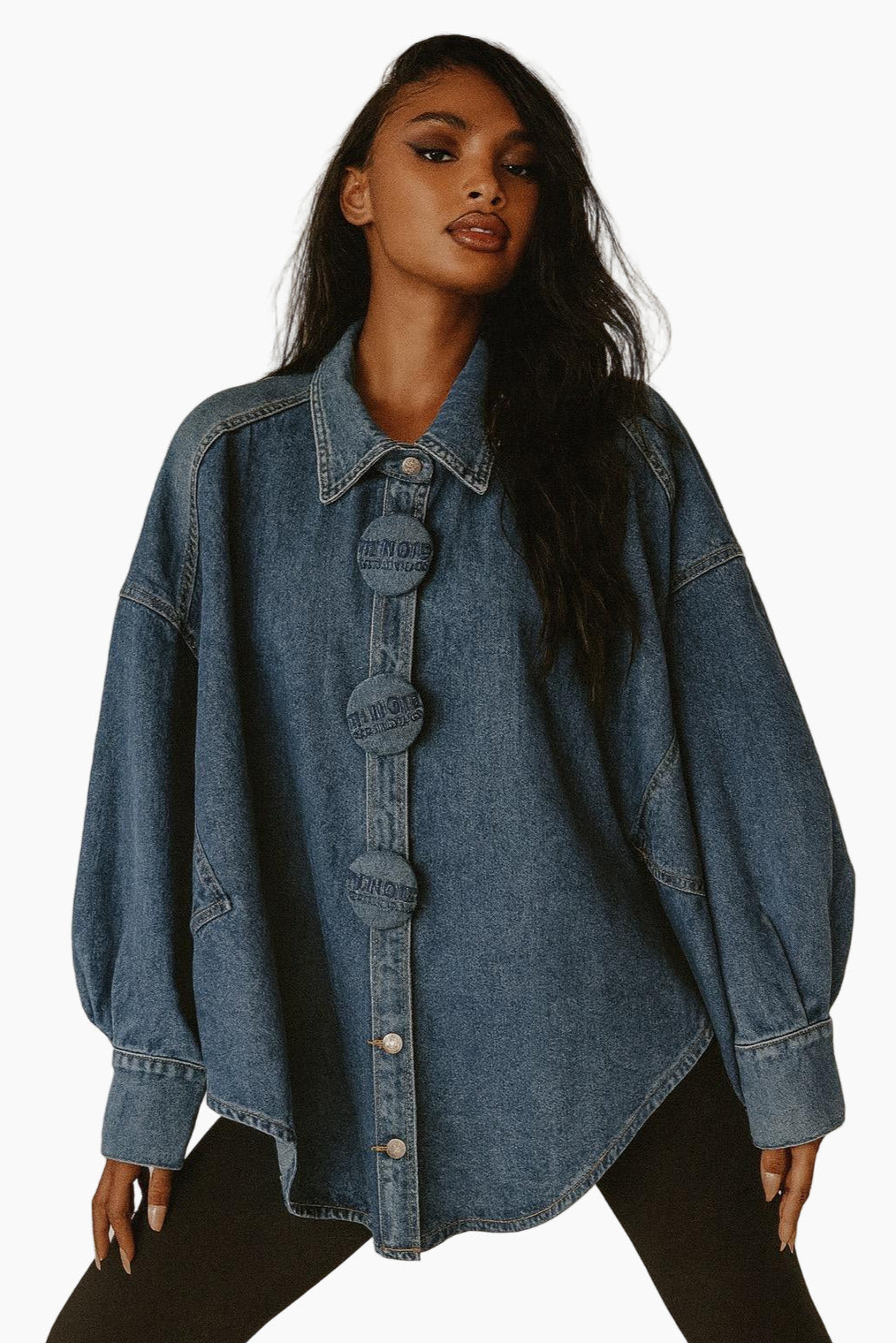 Woman wearing an oversized denim jacket on a white background