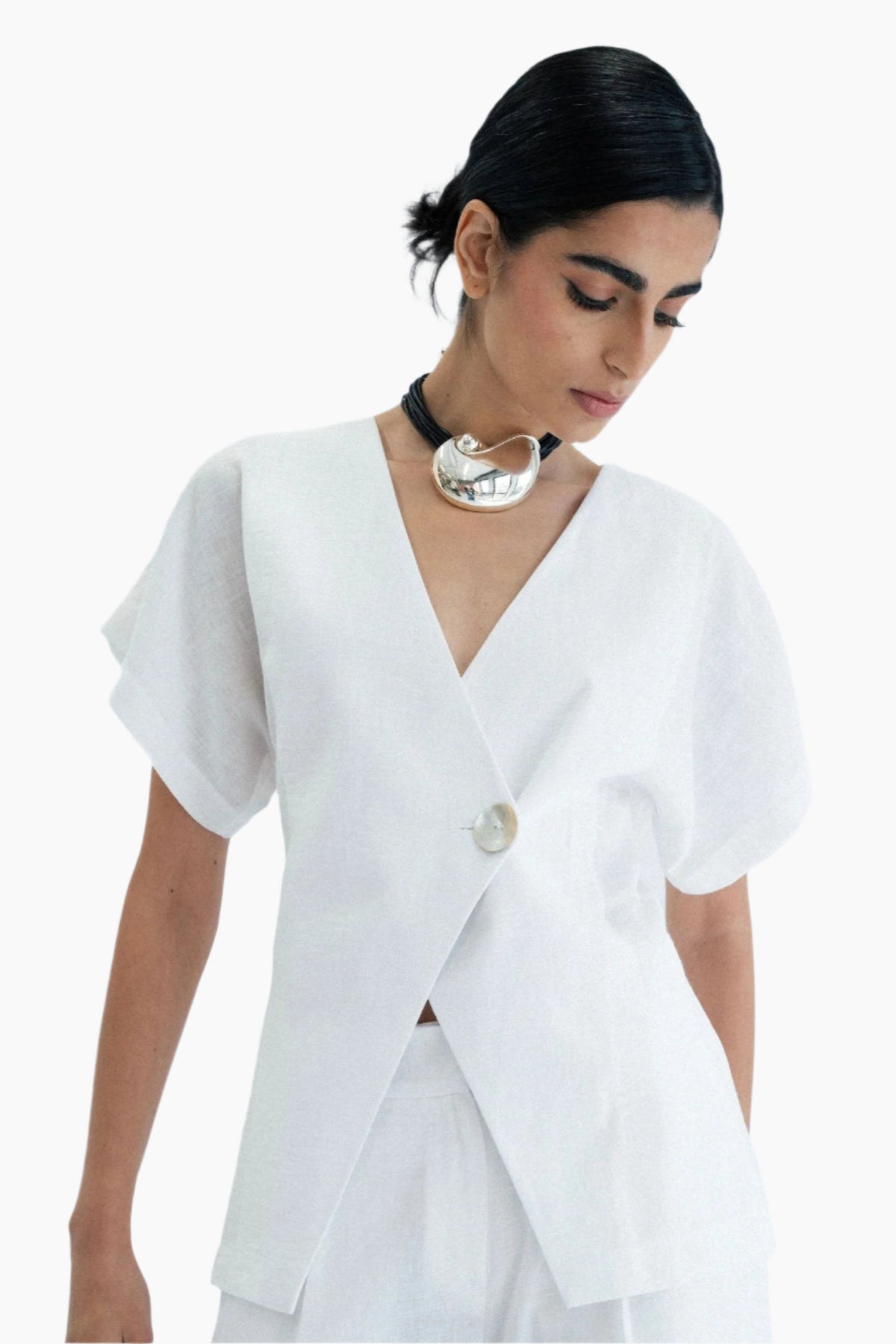Woman wearing a white outfit, shirt asymmetrical wrap design