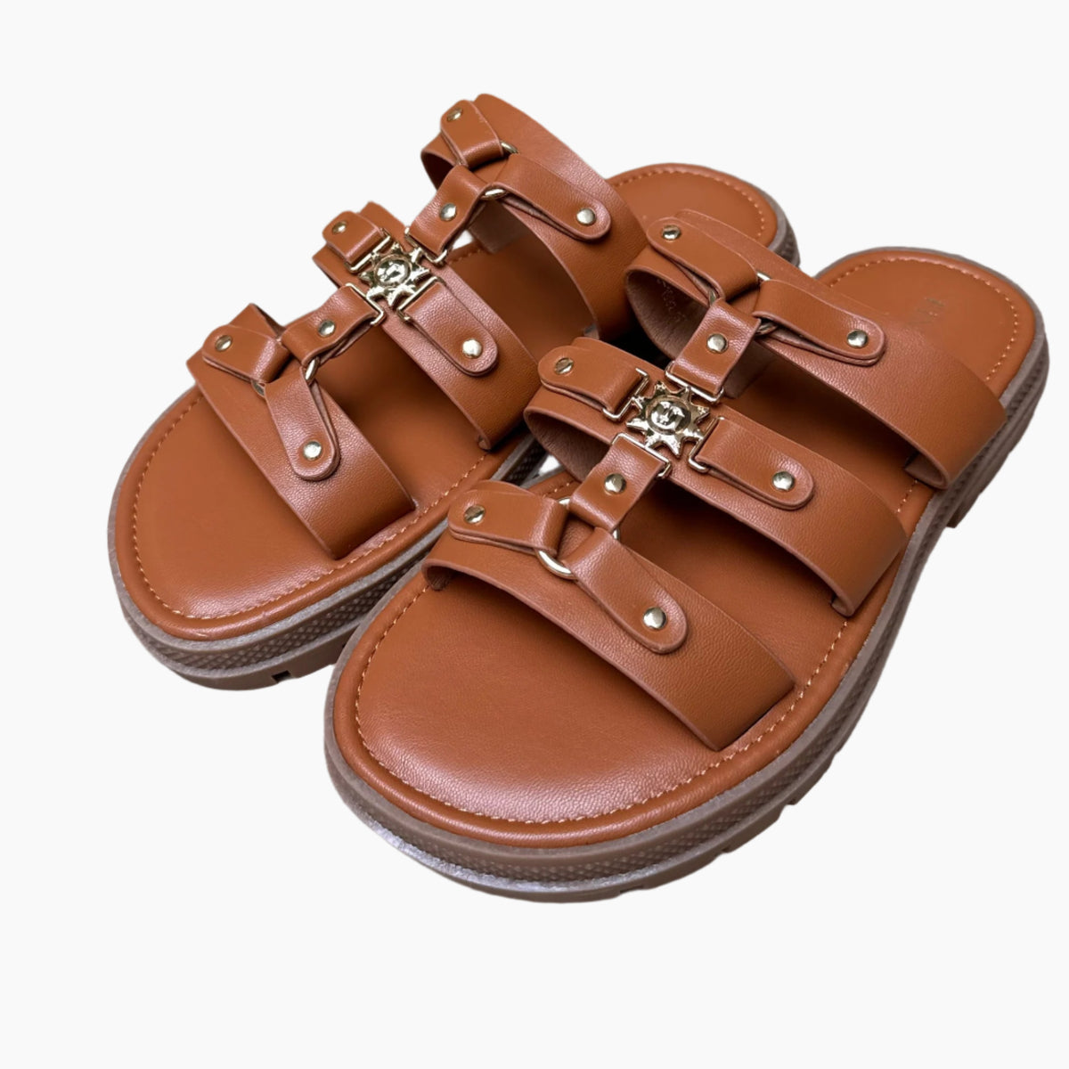 Brown leather sandals with buckles on a wooden surface