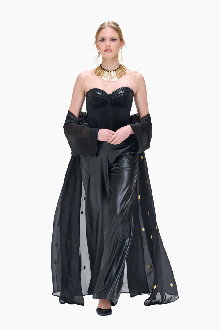 Woman wearing a black evening gown with gold accents on a white background