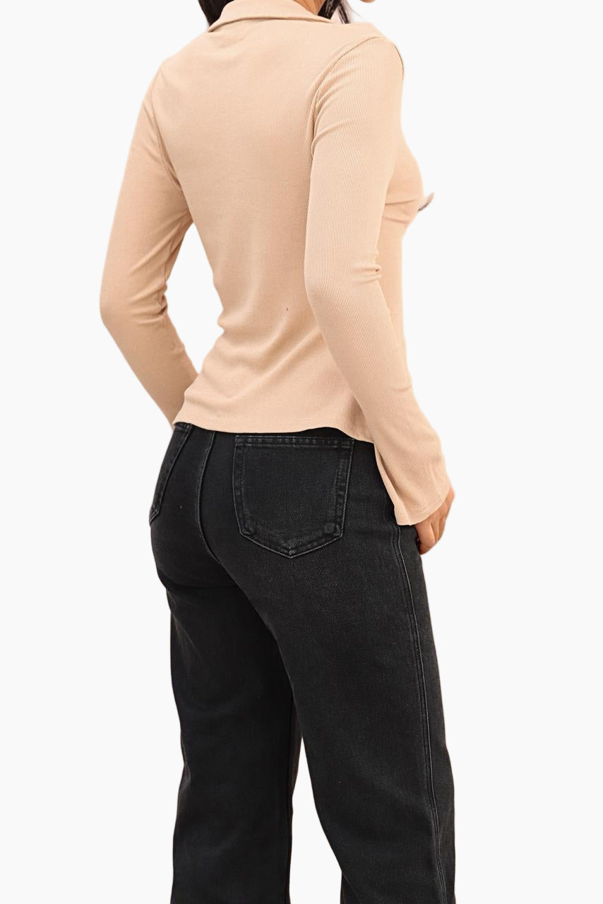 Person wearing a beige long-sleeve shirt and black jeans
