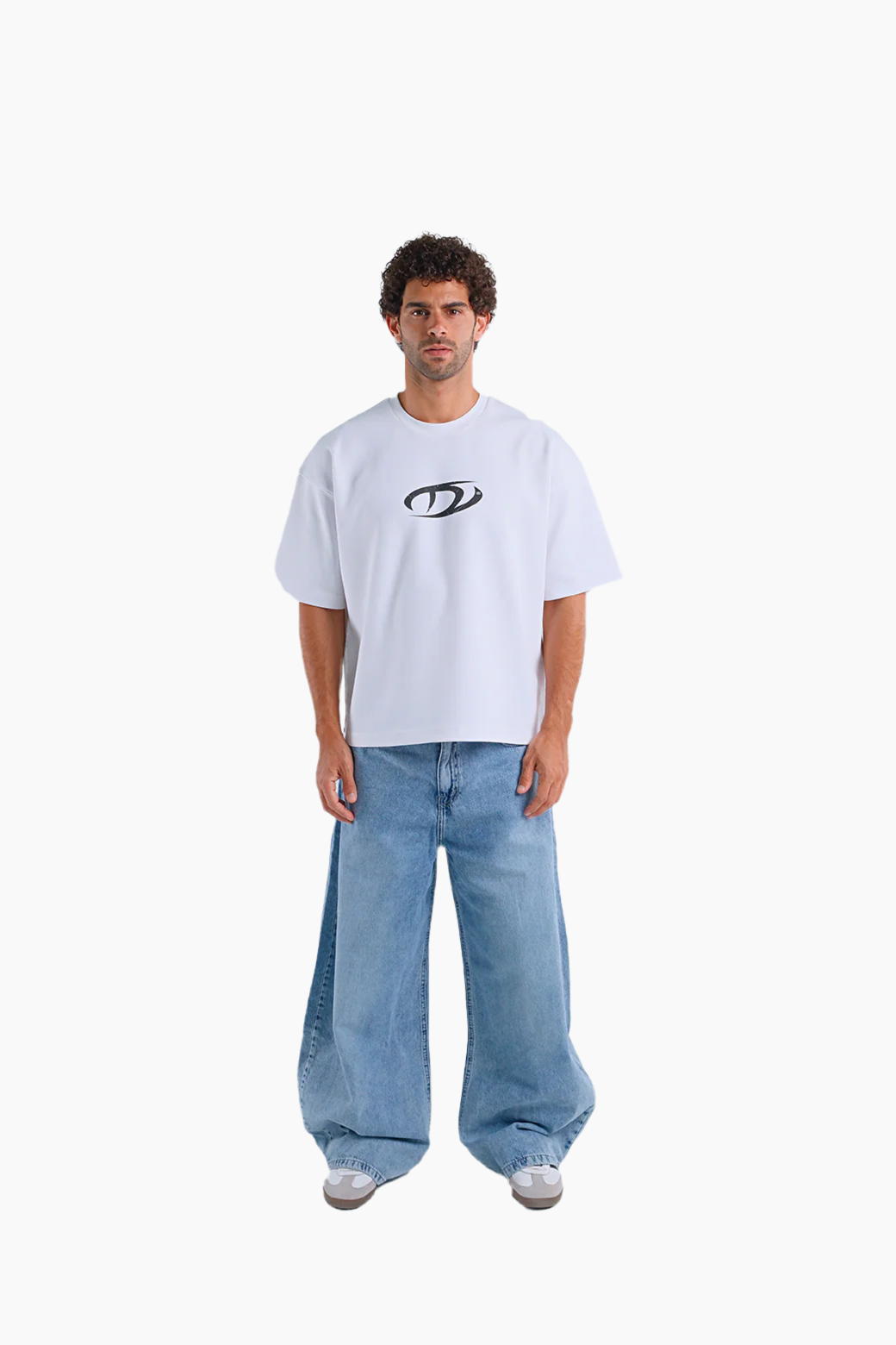 Person wearing a white t-shirt with a logo and blue jeans