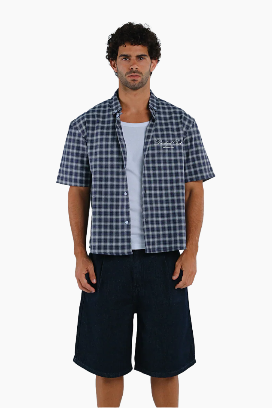 Man wearing a blue checkered shirt over a white t-shirt with navy shorts