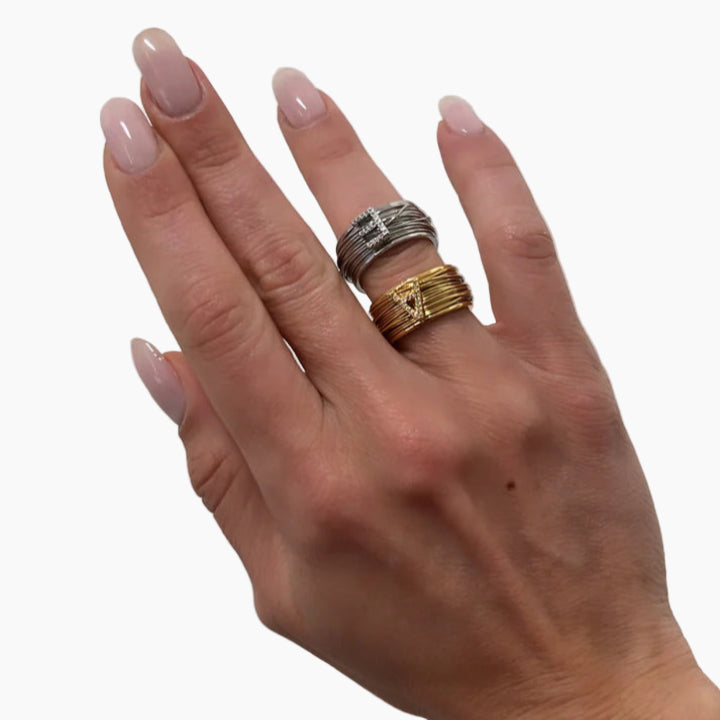 Hand wearing two rings on a plain background