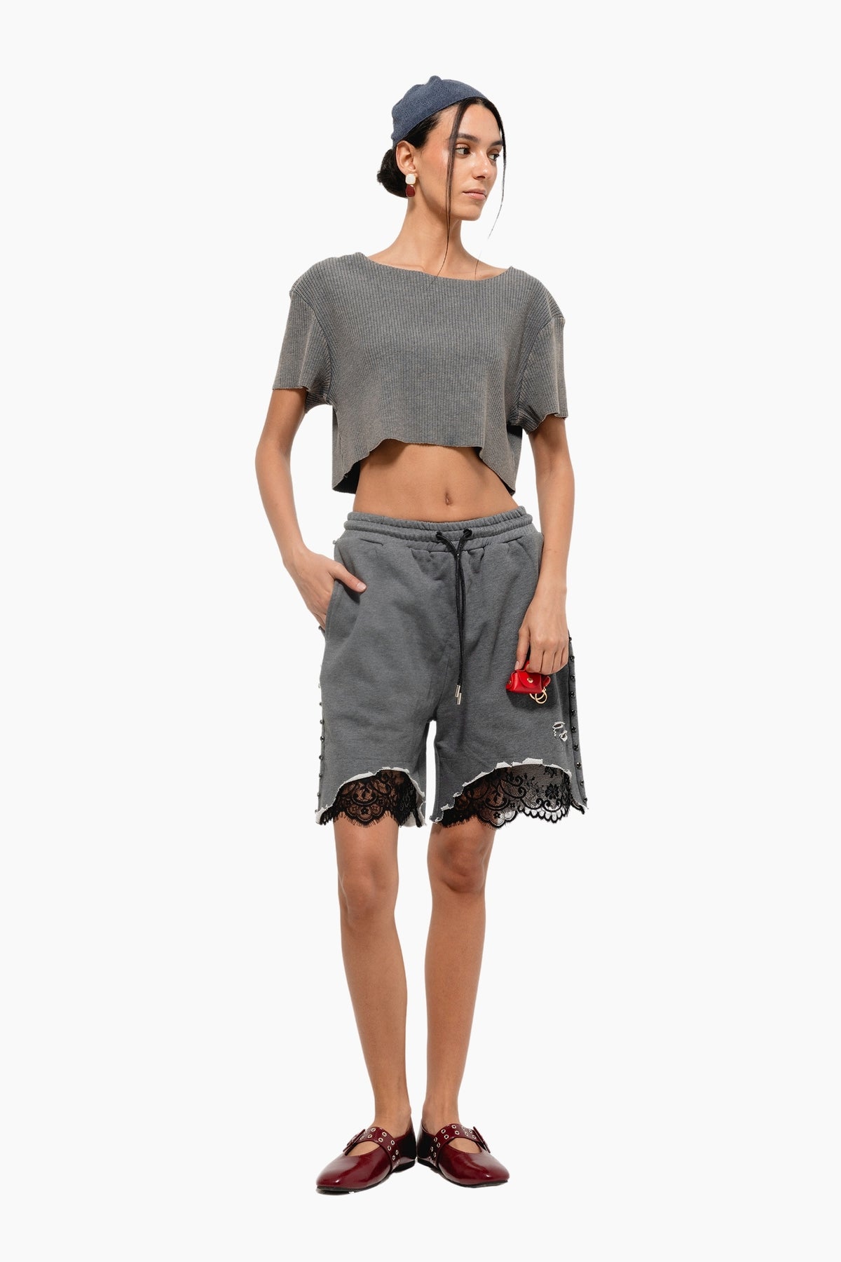Person wearing a gray outfit with lace details on shorts and a crop top.