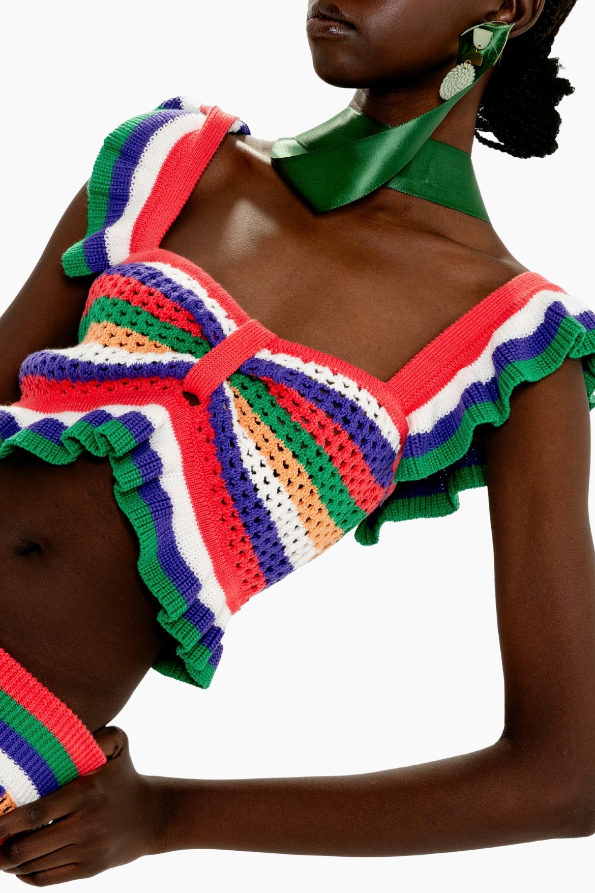 Person wearing a colorful crochet top with ruffled details on a white background