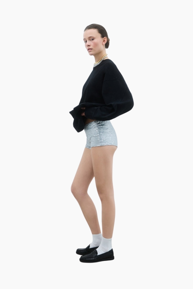 Person wearing a black sweater and light blue shorts