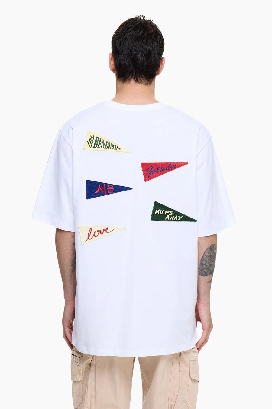 Person wearing a white t-shirt with colorful graphic designs on the back