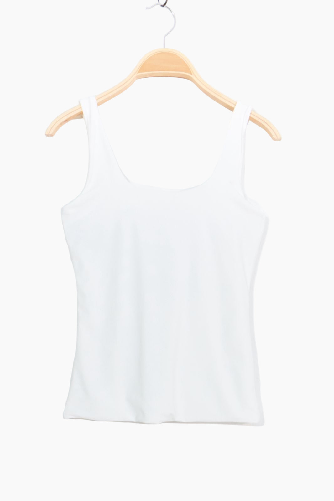 White tank top on a wooden hanger against a white background