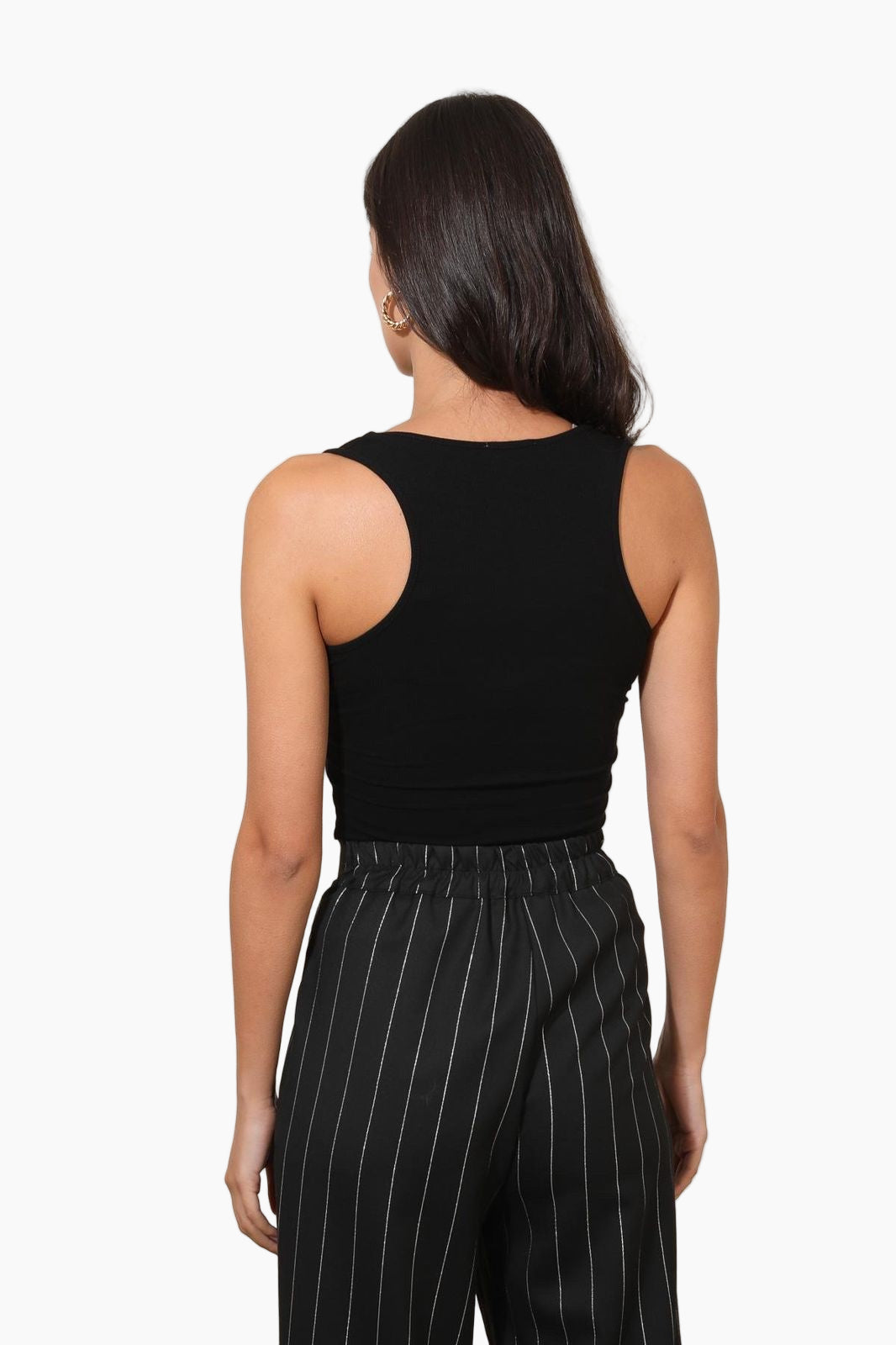 Person wearing a black sleeveless top and pinstripe pants