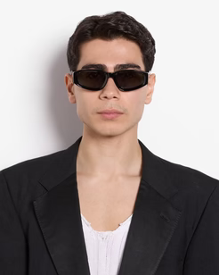 Man wearing sunglasses and a black blazer against a white background