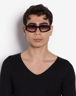 Person wearing dark sunglasses and a black shirt against a white background