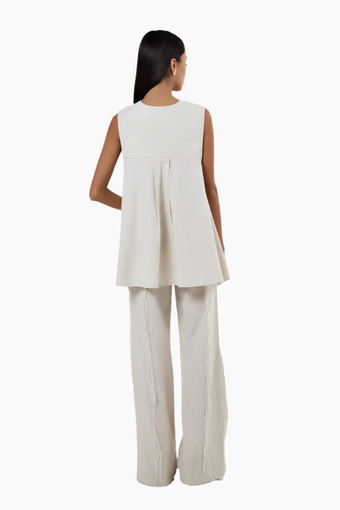 Woman wearing a white sleeveless top and pants
