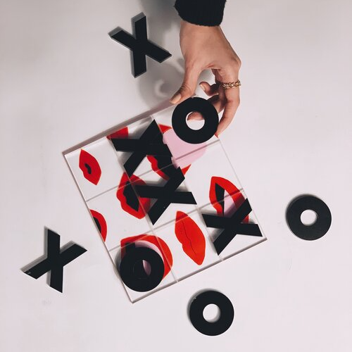 Hand holding a tile with 'XO' design on a white background