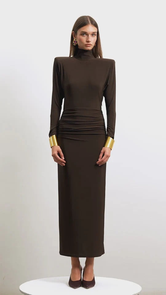 A model wearing a brown backless maxi dress with three-quarter sleeves and a V-neck neckline.