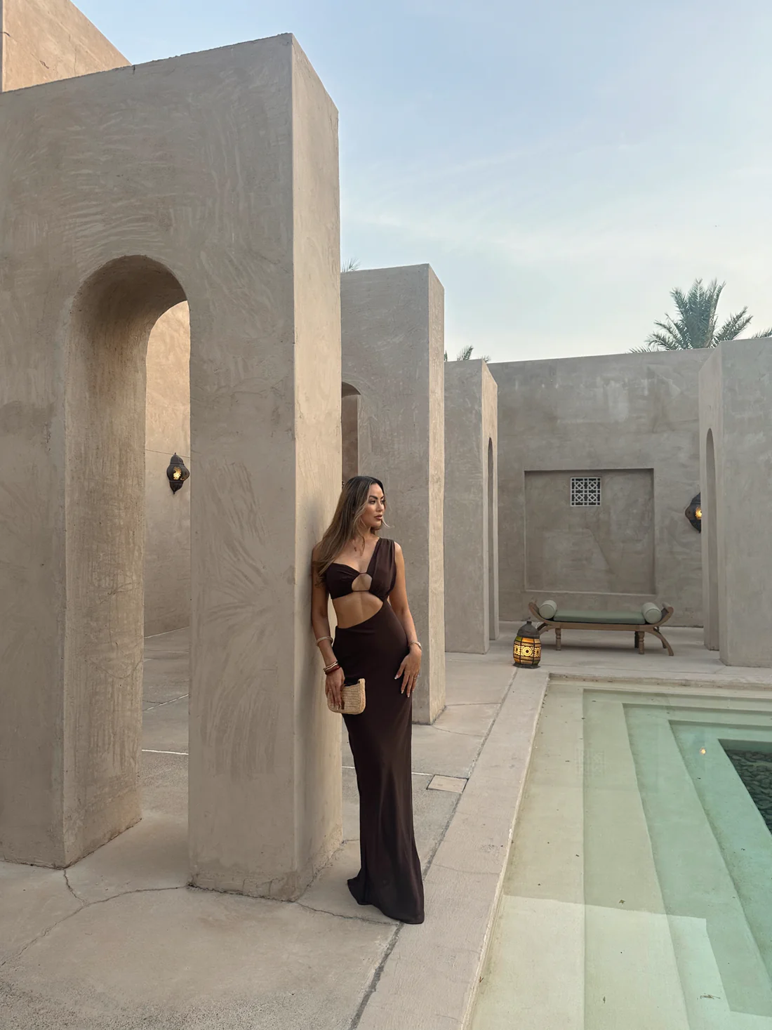 A woman in a chocolate brown maxi dress with a deep neckline and side split.