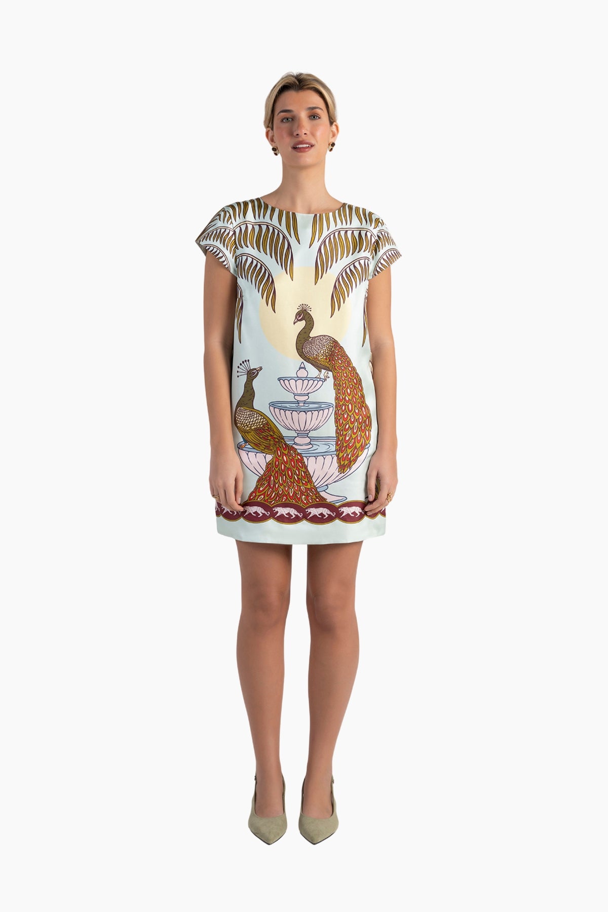 Woman wearing a dress with peacock design on a white background