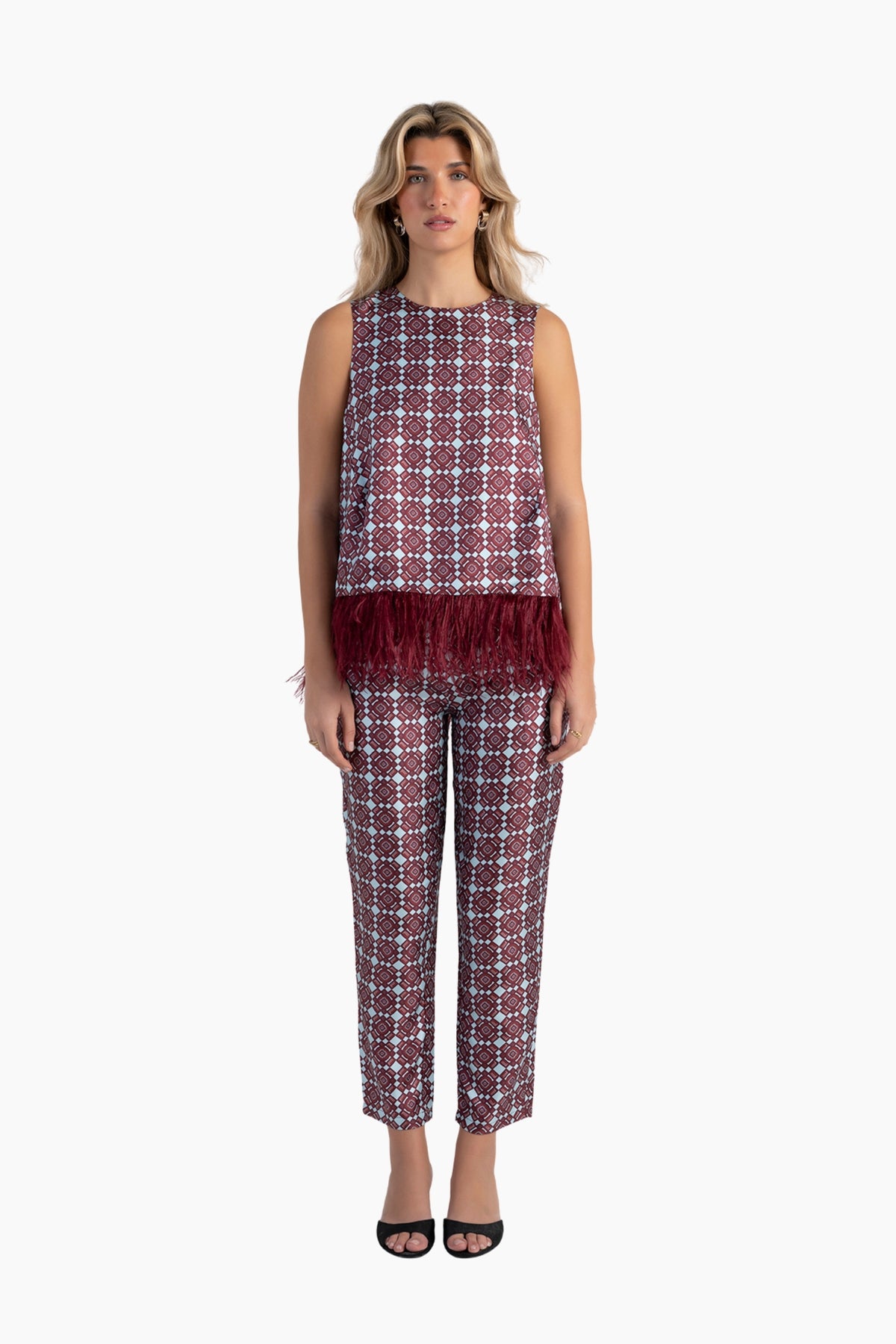 Woman wearing a patterned sleeveless top and pants on a white background