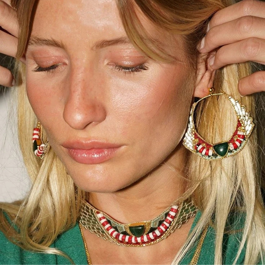Close-up of a woman wearing gold hoop earrings with red and green accents.