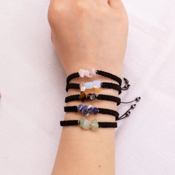 A series of bracelets with various colorful beads and a black thread, displayed on a person's wrist.