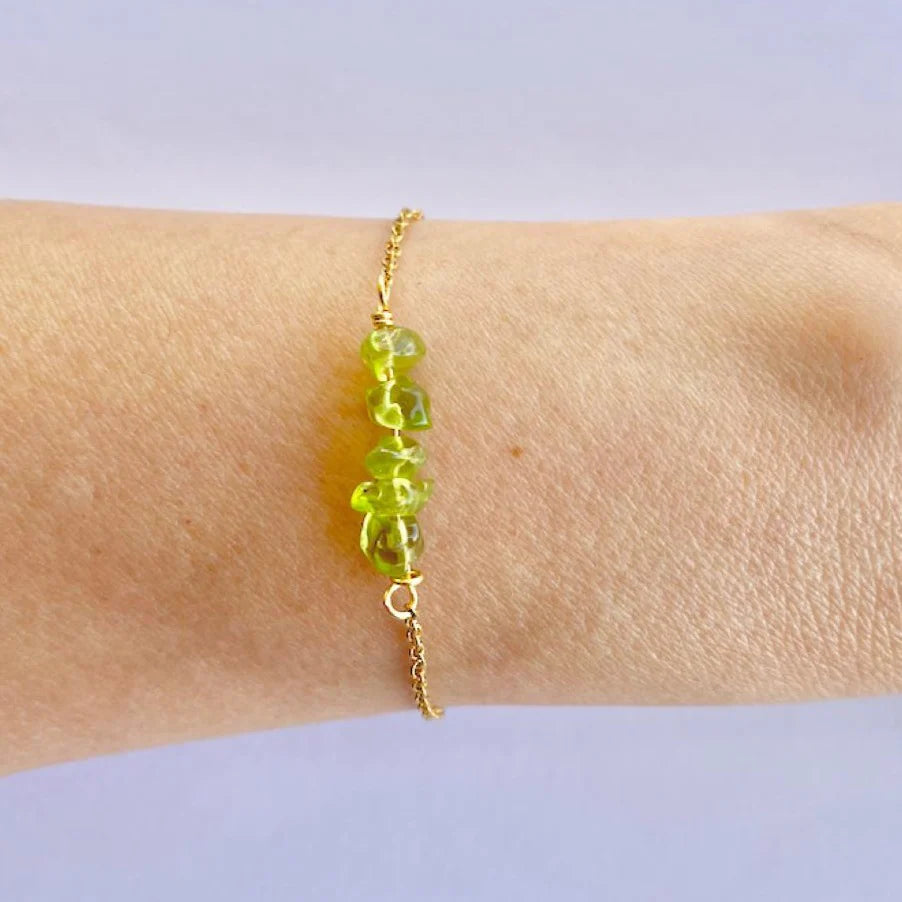 A bracelet with polished natural stones on a gold-colored stainless steel band, being worn on a person's wrist.