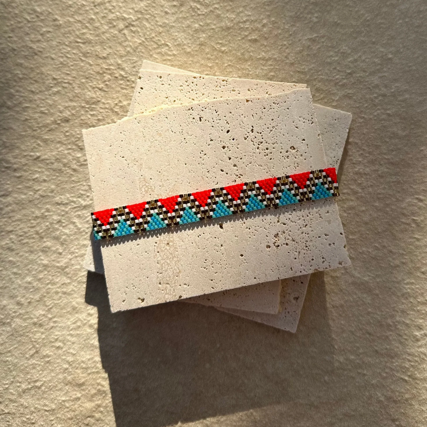 Beaded bracelet on a stack of paper with a textured background