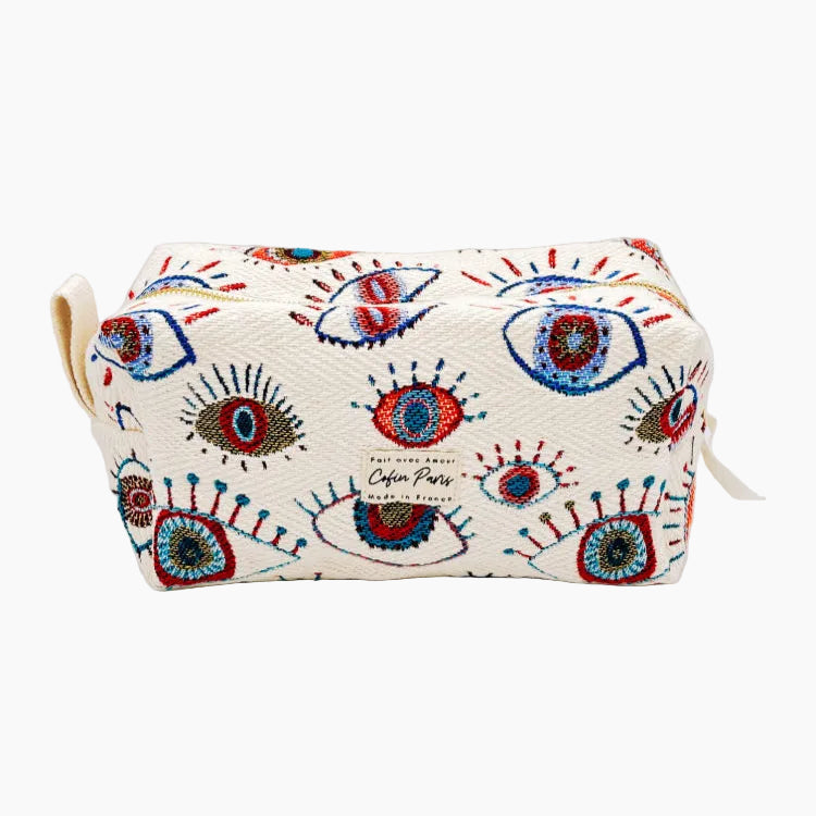 A multicolored cosmetic and toiletry bag with a geometric pattern featuring eye motifs on a white background, with a small handle and decorative elements.