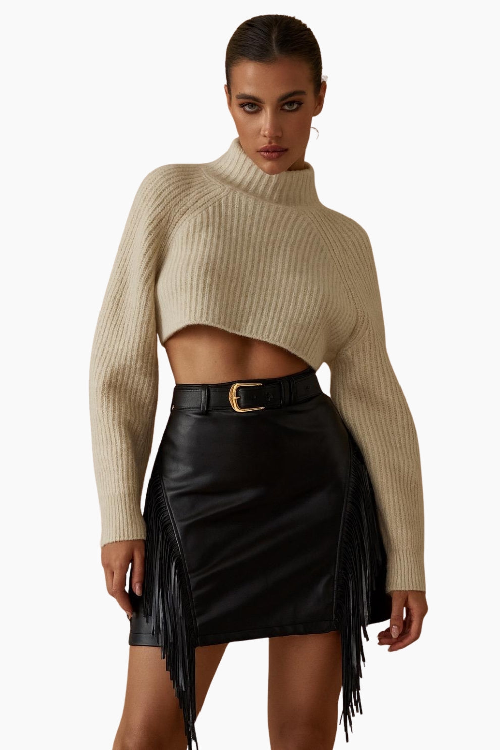 Woman wearing a beige ribbed sweater and black leather skirt with fringe