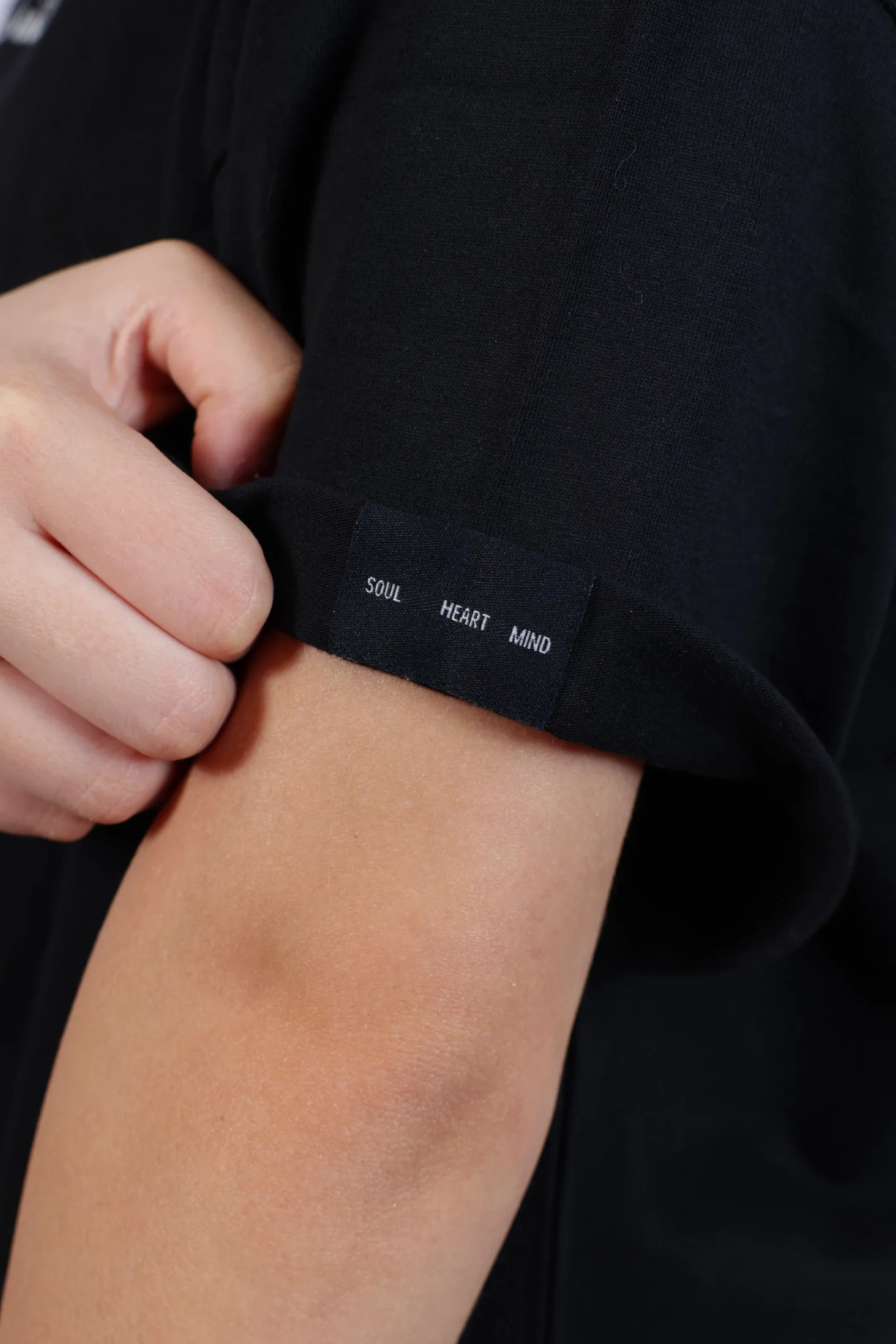 Close-up of a black sleeve with text and a hand adjusting it