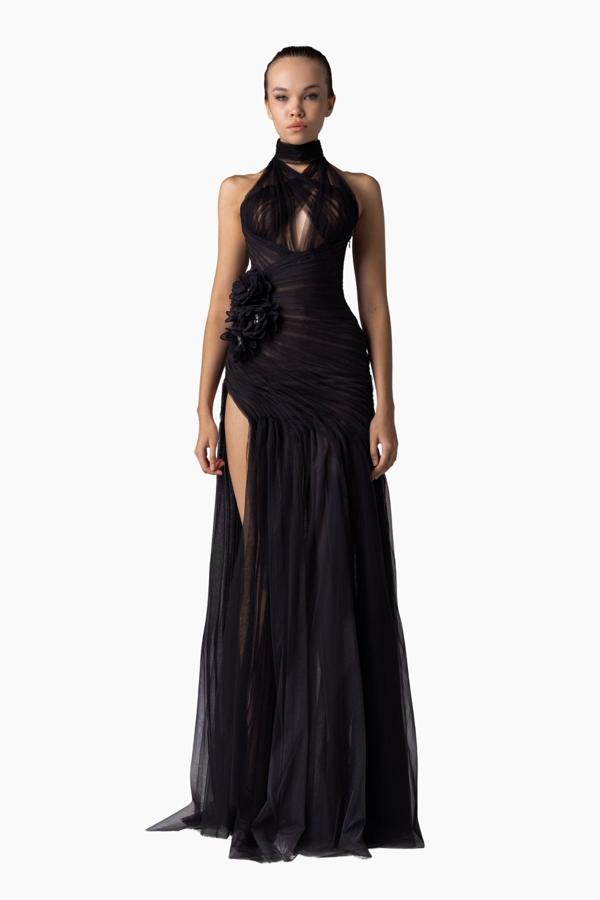 Woman wearing a black evening gown with floral details on a white background