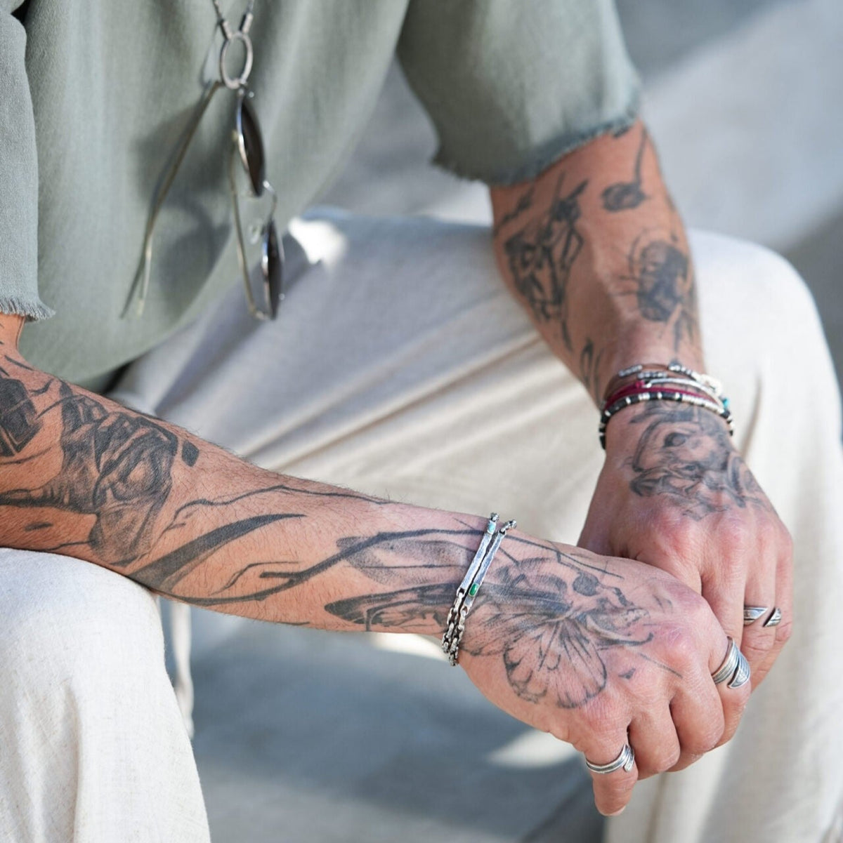 Two people holding hands with tattoos on their arms.