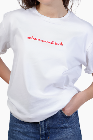Unisex White t-shirt with red text 'embrace.connect.trust.' worn by a person