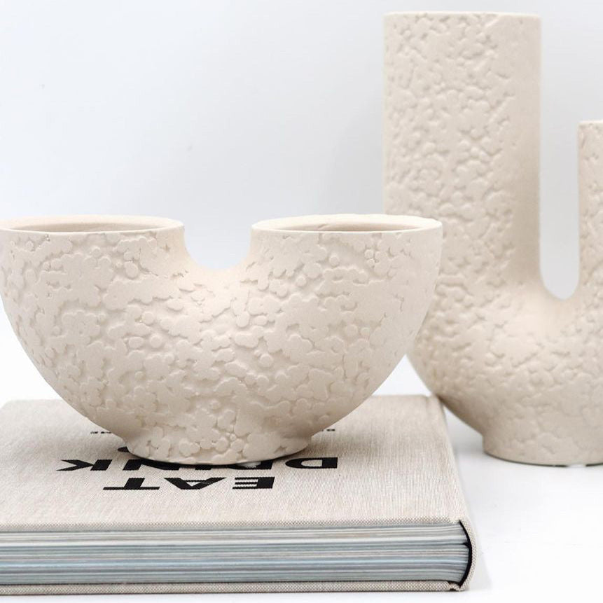 Textured ceramic bowls on a book with a white background