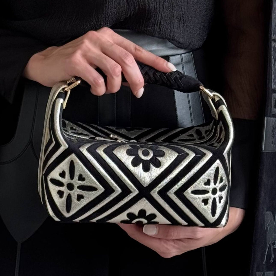 Person holding a black and white patterned handbag